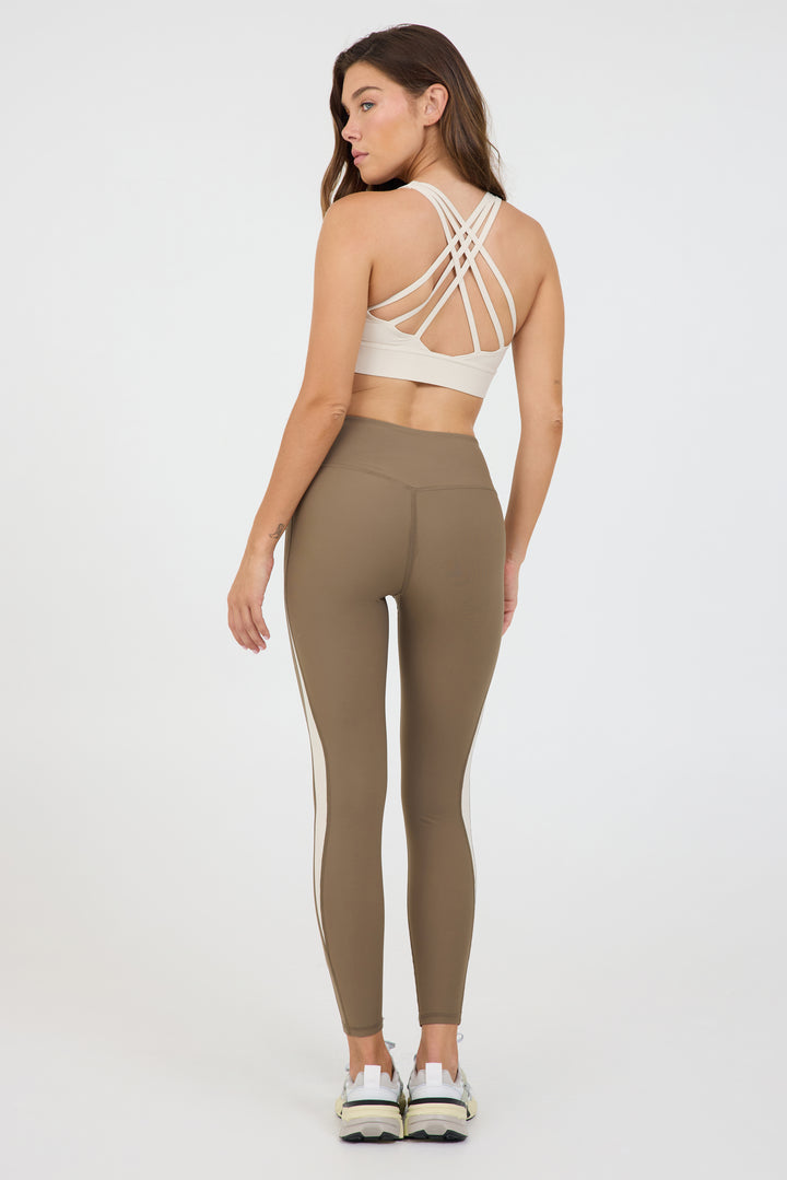 Carey strappy bra with removable bra cups in cream, modeled with the truffle and cream krista side panel 7/8 leggings from the back