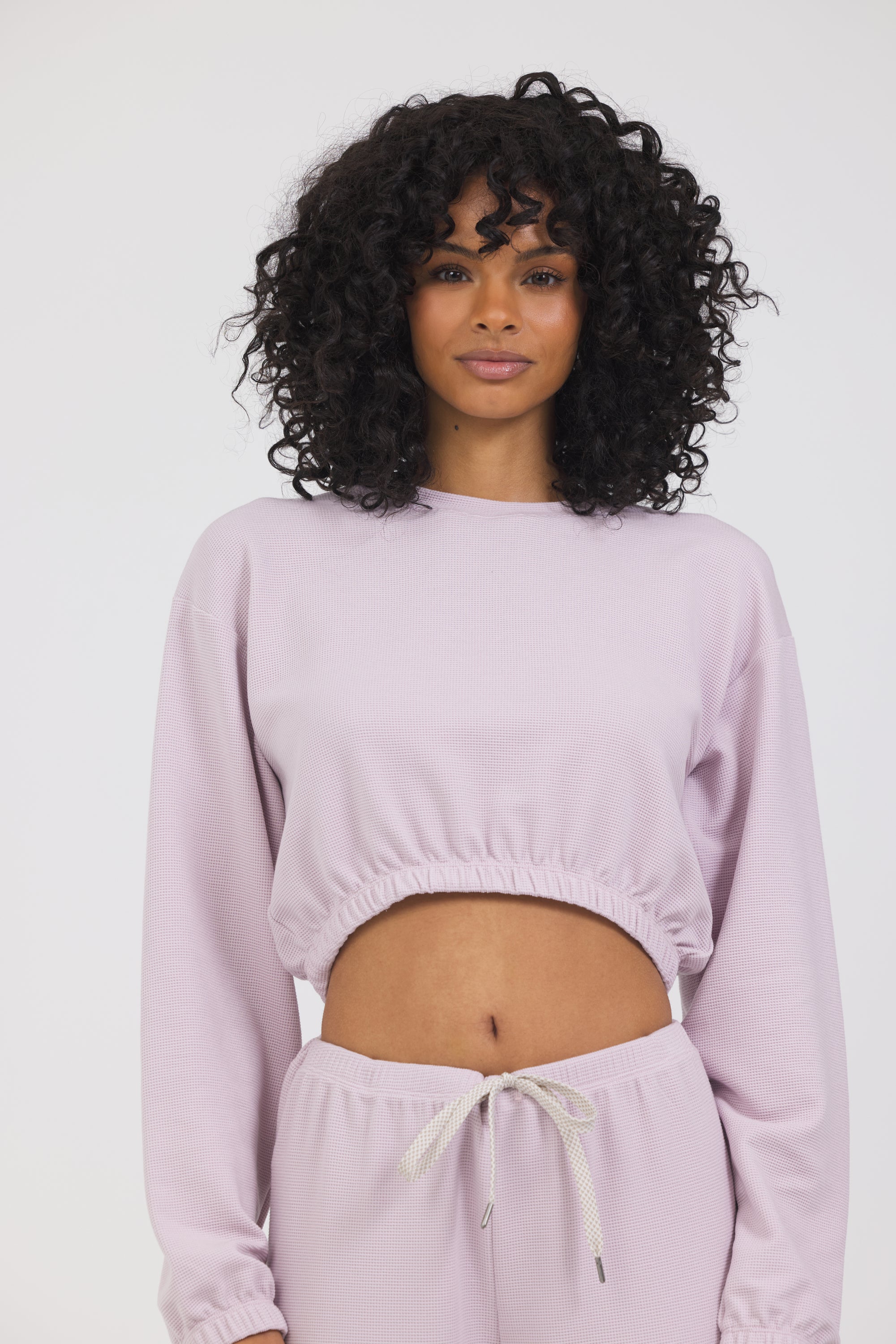 Caroline elasticized waist crop top with long sleeves and thumbholes in dusty pink, modeled with the Delaney joggers close front view