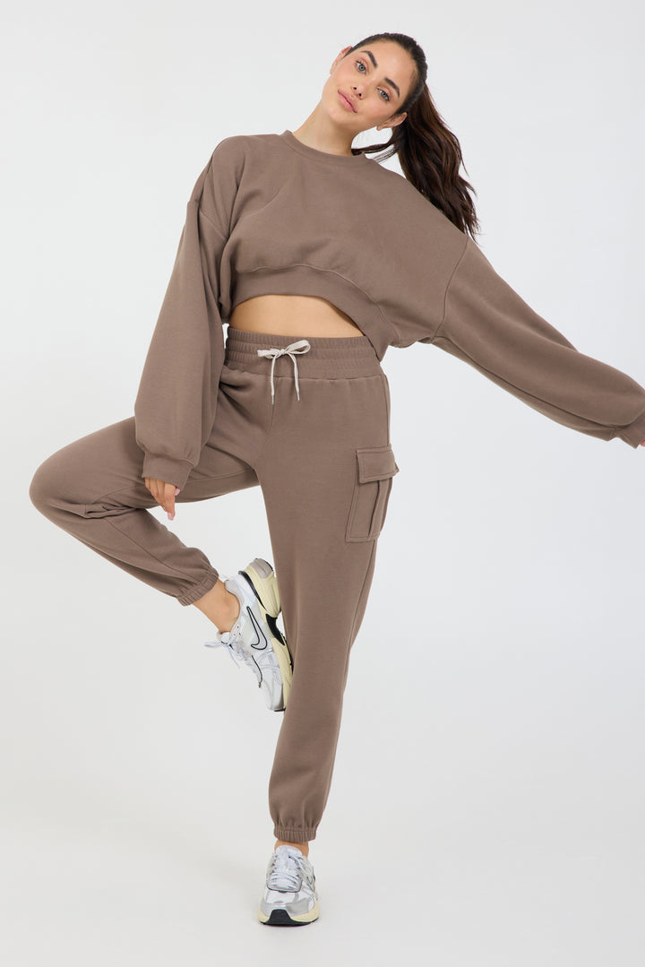 Claire fleece cropped long sleeve in dark truffle, modeled with the Kim Fleece cargo joggers from the front