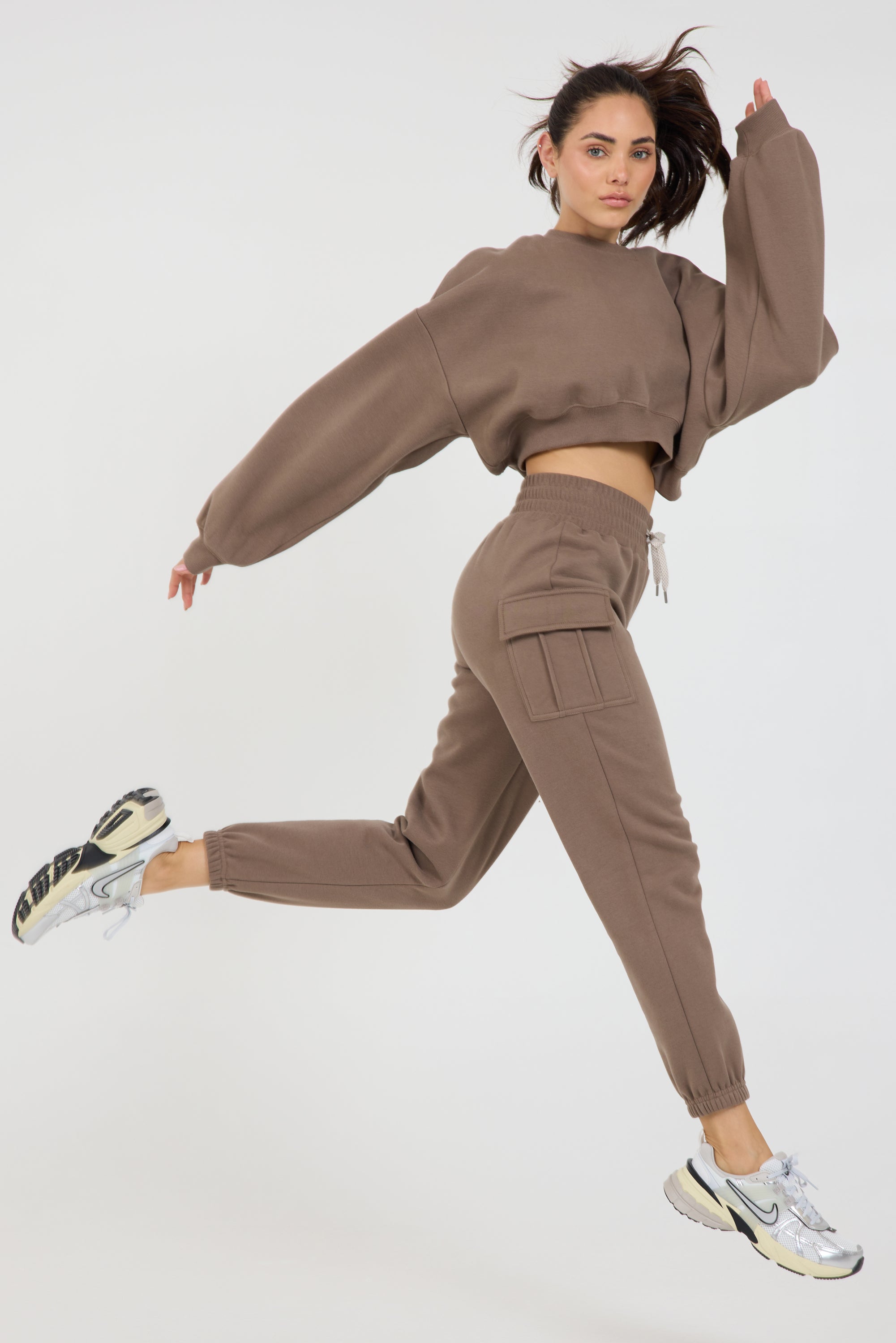 Claire fleece cropped long sleeve in dark truffle, modeled with the Kim Fleece cargo joggers shorts running from the side