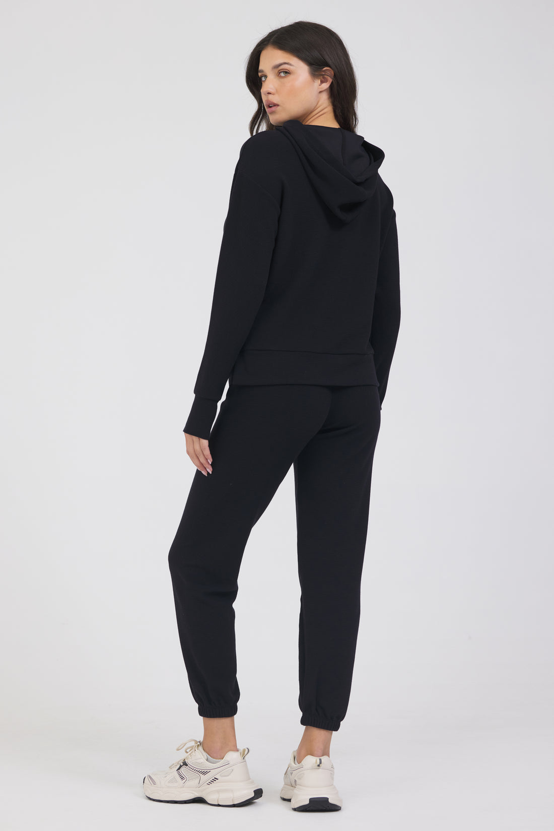 Delaney joggers in black, modeled with the Lynn pullover hoodie  with long sleeves and thumbholes from the back