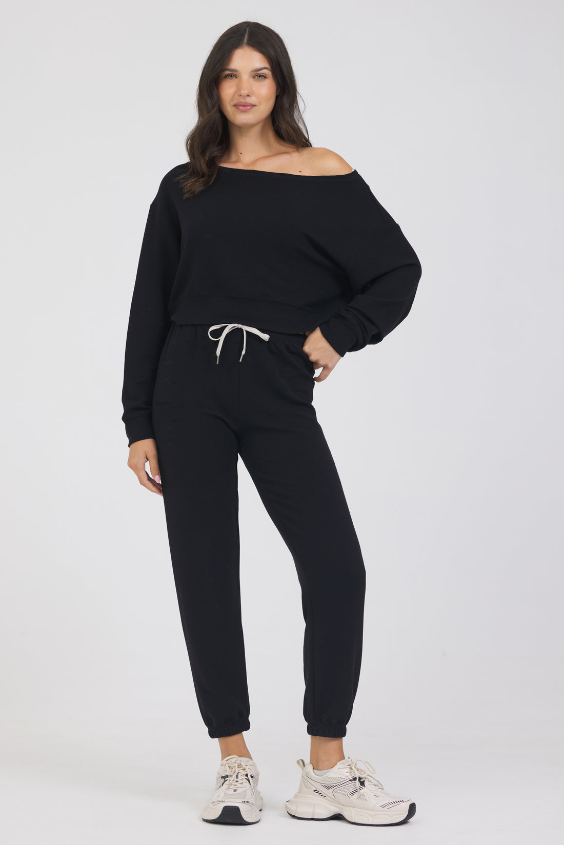 Delaney joggers in black, modeled with the Amiee off the shoulder long sleeve from the front