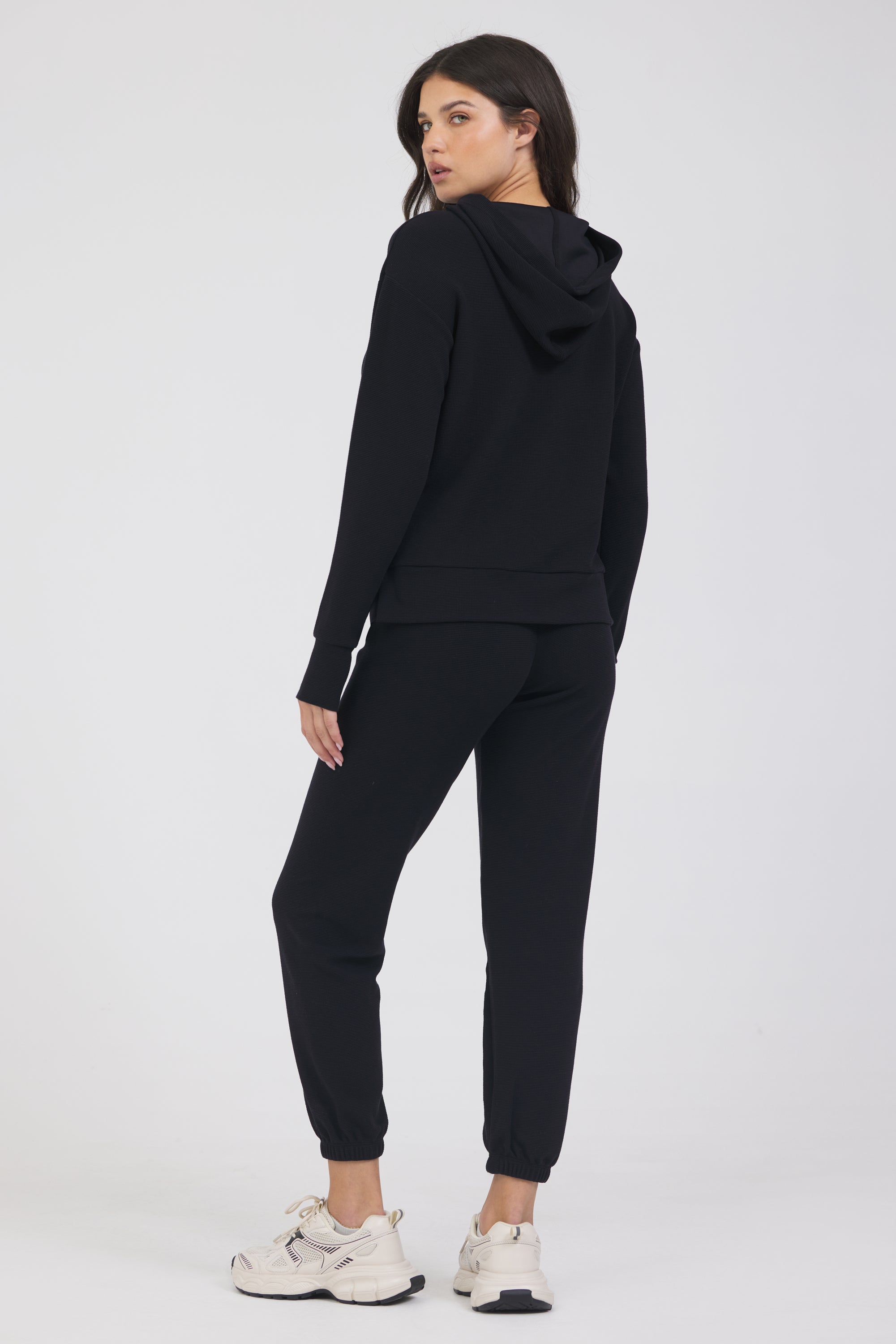 Lynn pullover hoodie with long sleeves in black, modeled with the Delaney joggers from the back