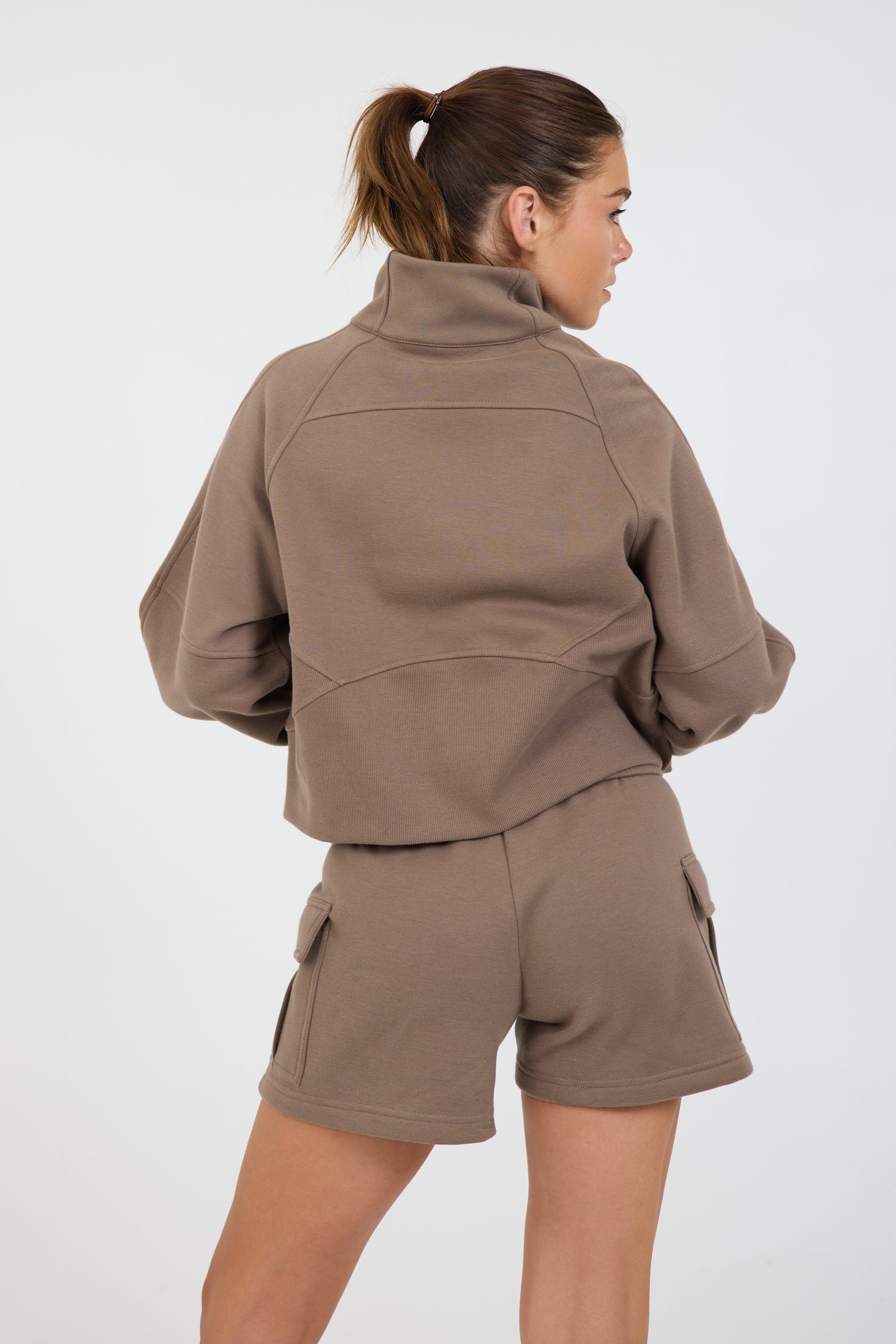 Sam fleece cargo shorts in dark truffle, modeled with the elasticized waist tank and the Nicole Fleece zipped cropped hoodie from the back